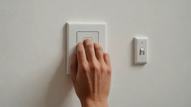 Mão desligando o interruptor de luz em casa